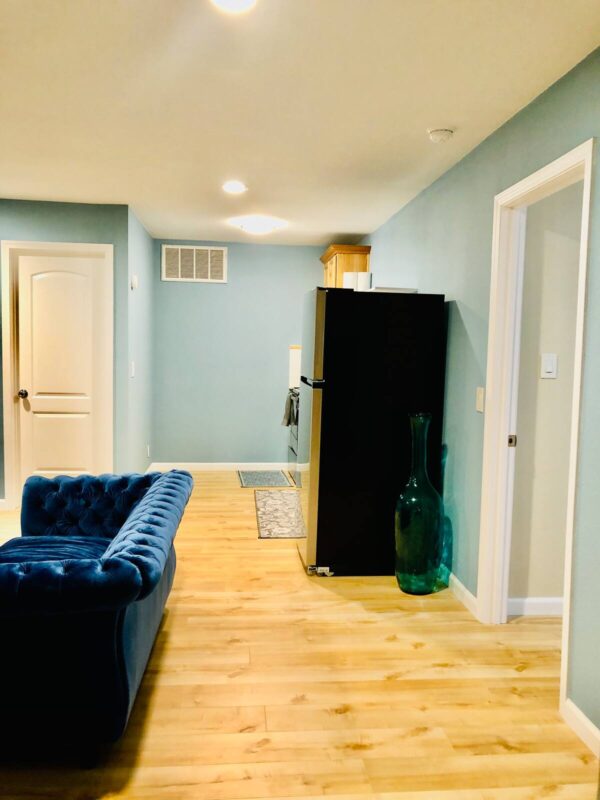 A blue couch and refrigerator in the living room.