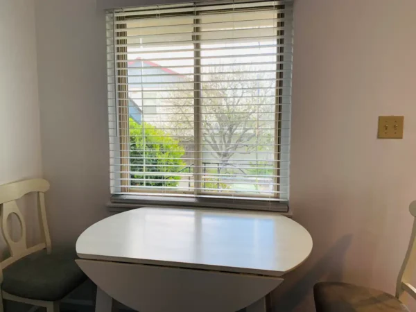 A table in front of a window with blinds on it.