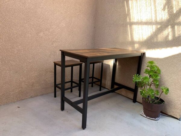 A table with two stools and a plant in the corner.