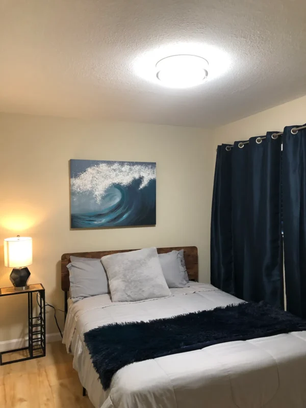 A bedroom with a bed, nightstand and lamp.