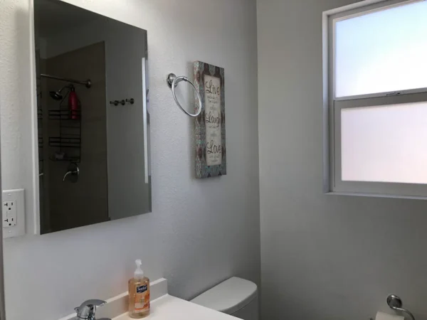 A bathroom with a sink, mirror and window.