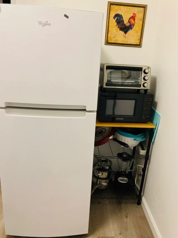 A refrigerator with two microwaves on top of it.