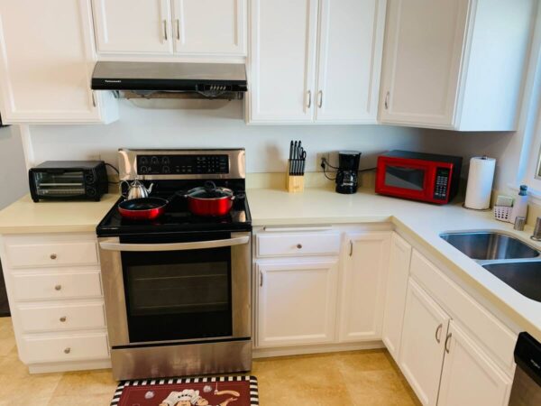 A kitchen with white cabinets and red microwave.