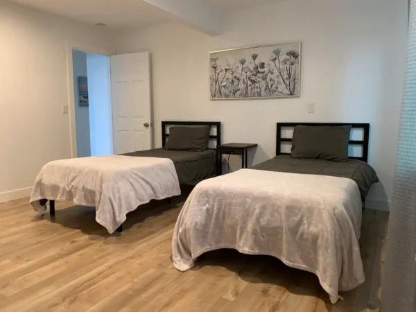 A bedroom with two beds and a painting on the wall.