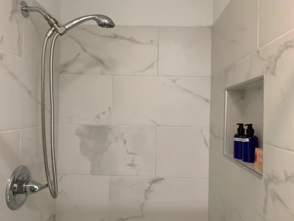 A shower with marble walls and white tile.