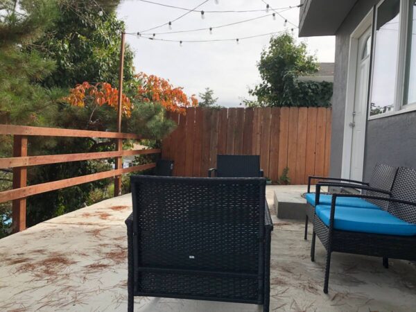 A patio with a black chair and blue table.