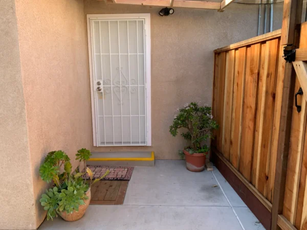 A small patio with potted plants and a door.