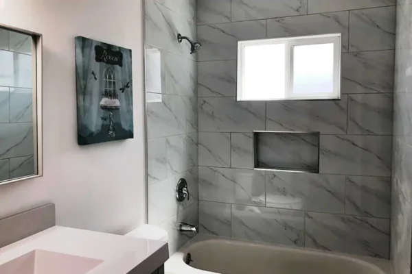 A bathroom with marble walls and white fixtures.