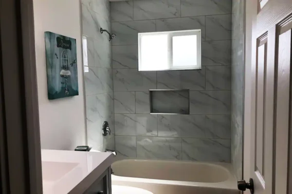 A bathroom with marble walls and white fixtures.