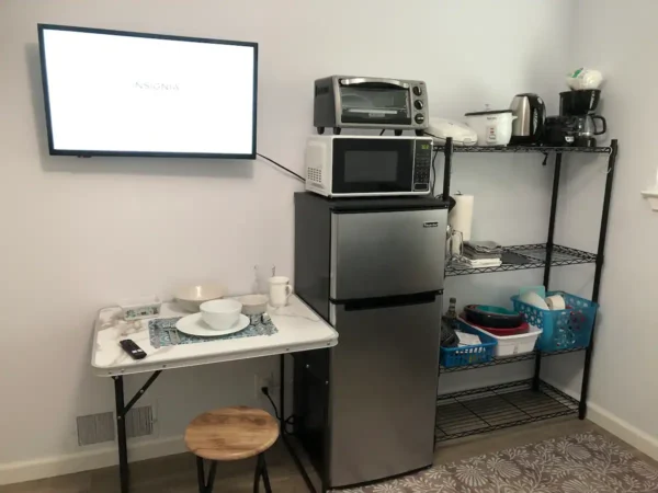 A room with a table, microwave and refrigerator.