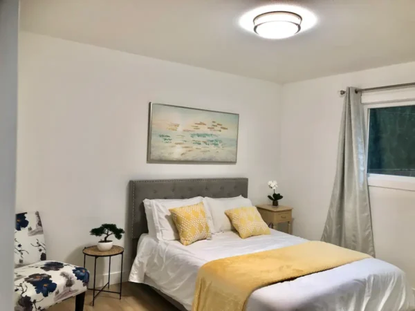 A bedroom with a bed, nightstand and window.