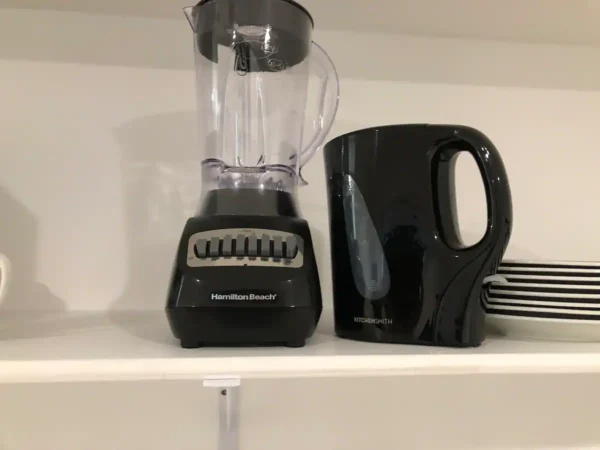 A blender and coffee pot on top of a shelf.