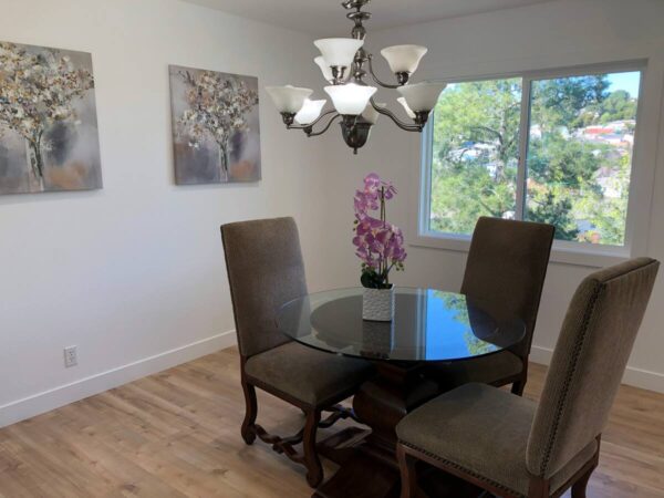 A dining room table with four chairs and a chandelier.