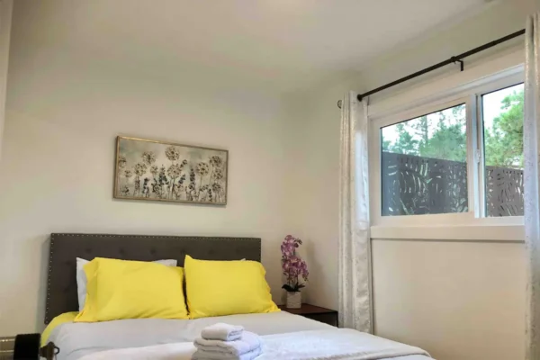 A bed room with a white bed and yellow pillows