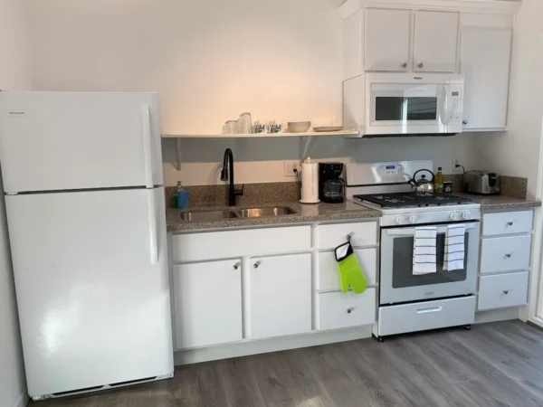 A kitchen with white cabinets and appliances.