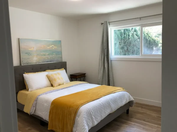 A bedroom with a bed, nightstand and window.