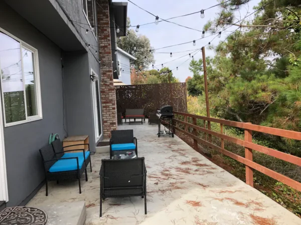 A patio with chairs and tables on the side of the house.