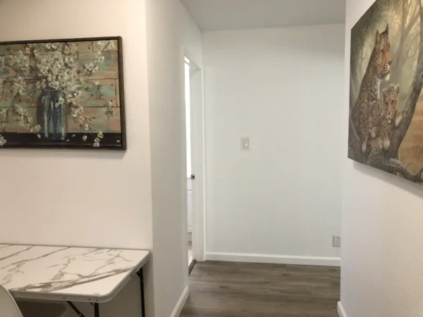 A hallway with a table and a painting on the wall.