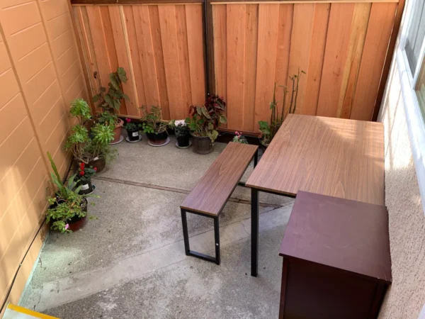 A table and bench in the corner of an outdoor room.