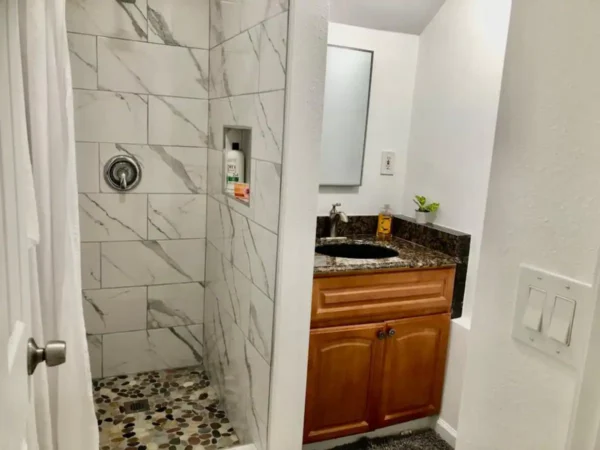 A bathroom with a walk in shower and a sink.