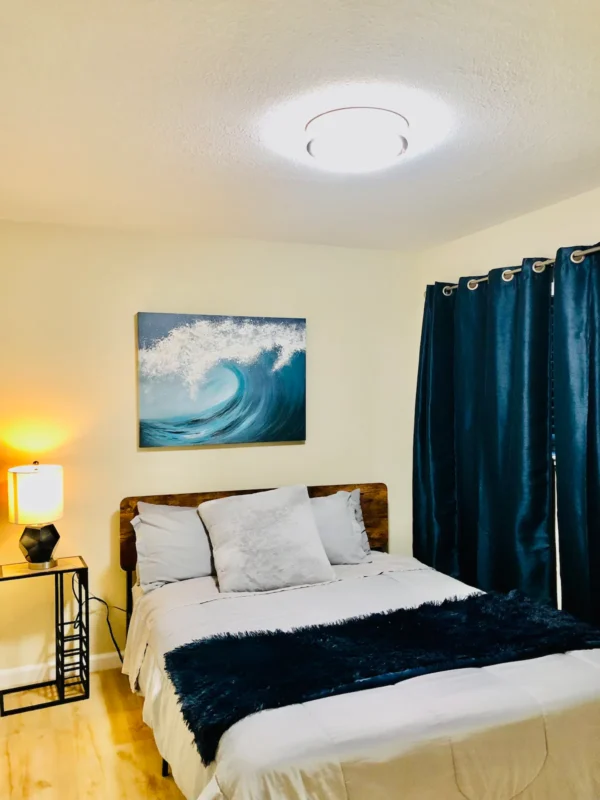 A bedroom with a bed, nightstand and lamp.