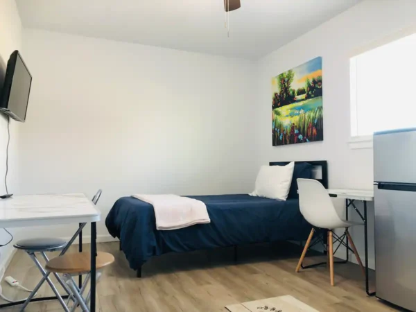 A bedroom with a bed, desk and chair.