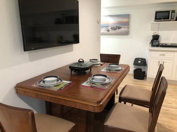 A dining room table with four chairs and a tv.