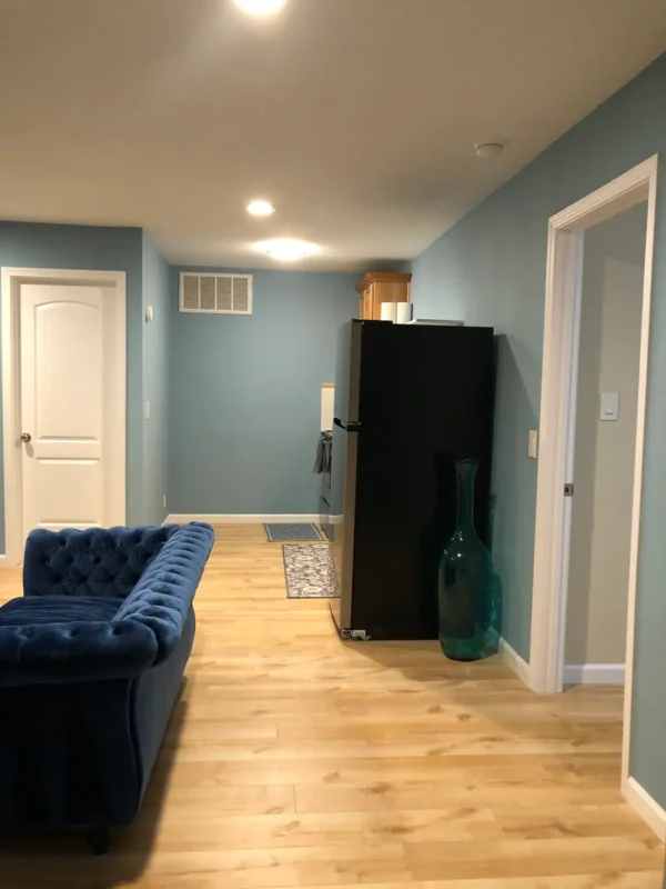 A blue couch and refrigerator in the middle of a room.