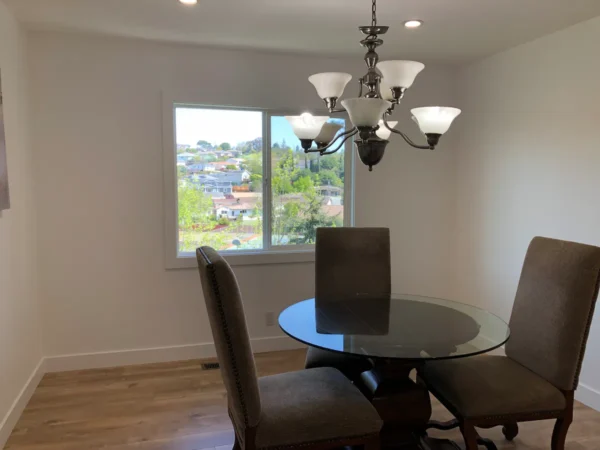 A dining room table with chairs and a chandelier.