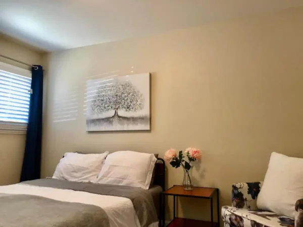 A bedroom with a bed, nightstand and a painting.