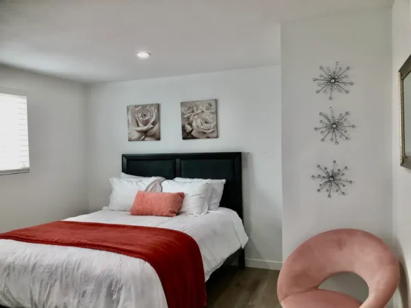 A bedroom with a bed, chair and wall decorations.