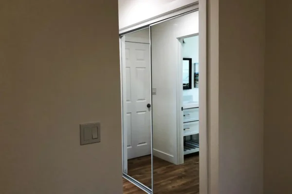 A mirror in the corner of a room with a door open.