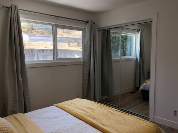 A bedroom with a large mirror and a wooden bed.