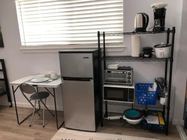 A kitchen with a table and chairs, microwave, toaster oven, refrigerator.