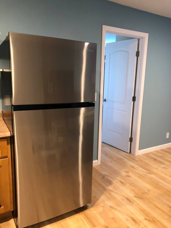 A stainless steel refrigerator in the middle of a kitchen.