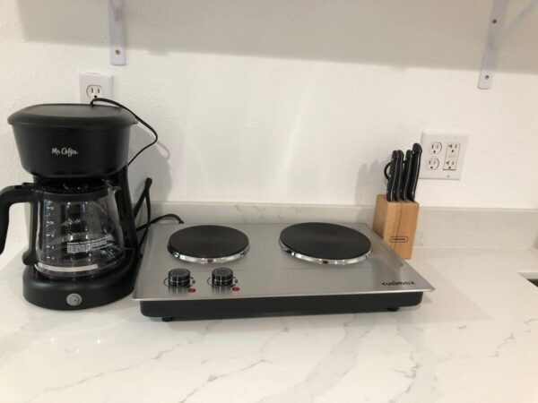 A coffee pot and two burners on the counter.