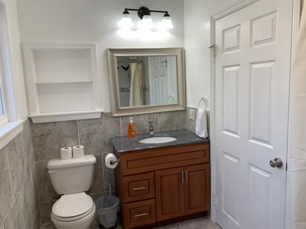 A bathroom with a toilet, sink and mirror.