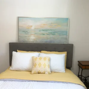 A bed with pillows and a painting on the wall.