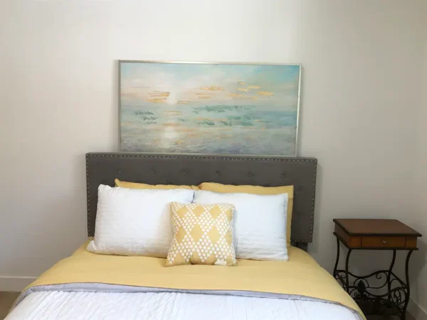 A bed with pillows and a painting on the wall.