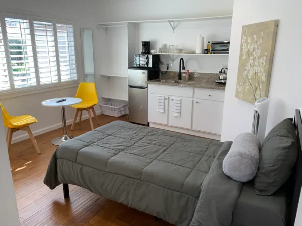 A bedroom with a bed, coffee maker and microwave.