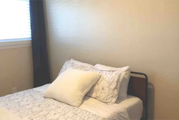 A bed with white sheets and pillows on it