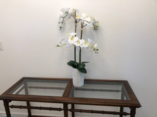 A white flower pot sitting on top of a table.