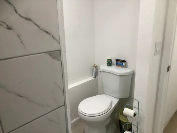 A bathroom with white walls and a toilet.