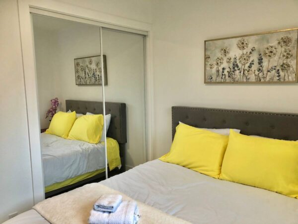 A bedroom with yellow pillows and a white bed.