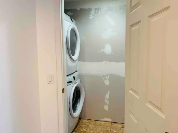 A small room with two white appliances and a door.