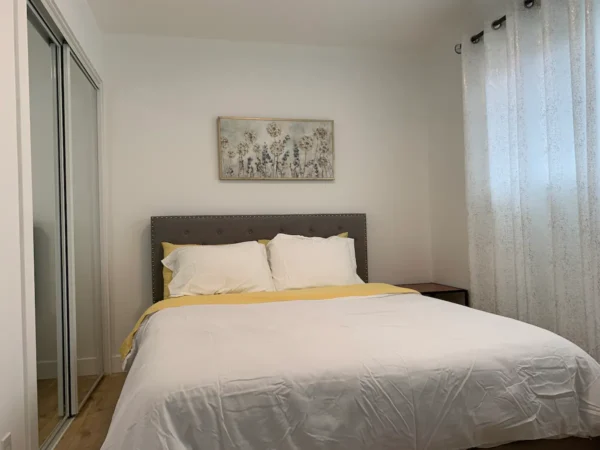 A bed room with a white and yellow bedspread