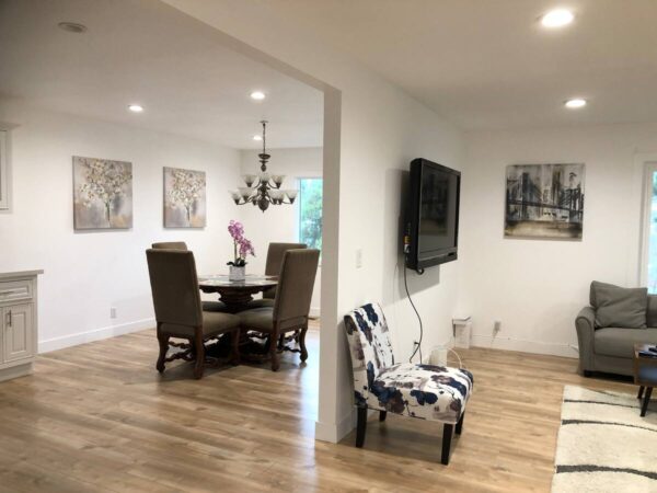 A room with a table, chairs and television.