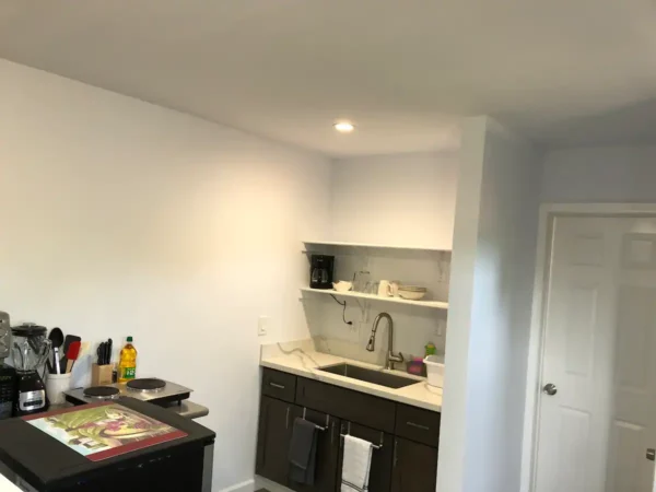 A kitchen with white walls and black cabinets.