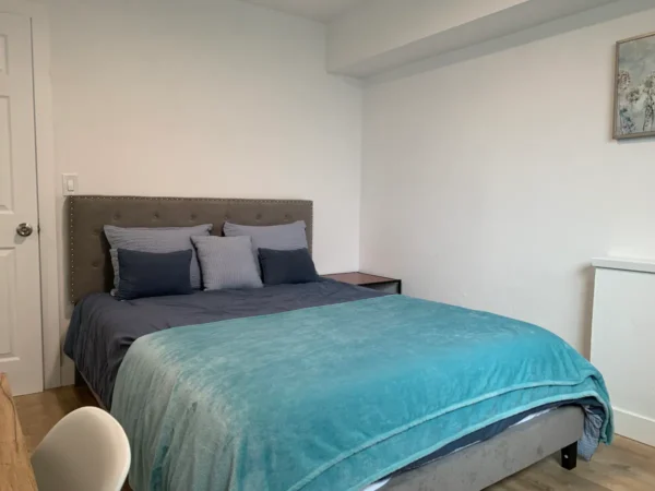 A bed room with a blue bedspread and pillows