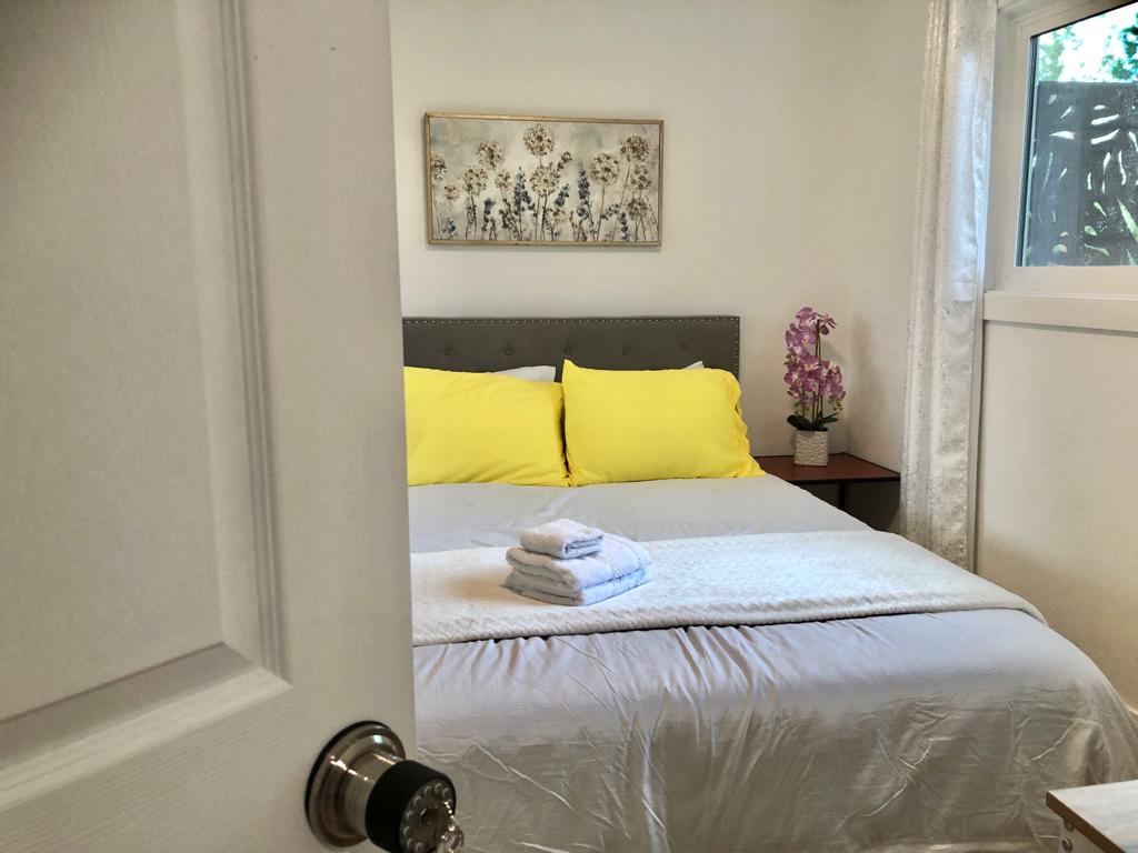 A bedroom with yellow pillows and white sheets.